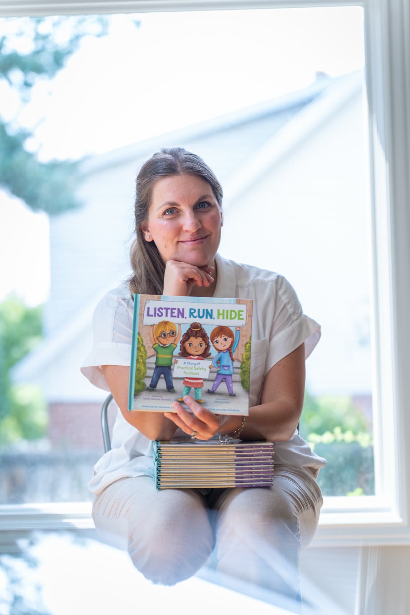 Emily Romrell, children's book author and school safety educator, holding Listen Run Hide