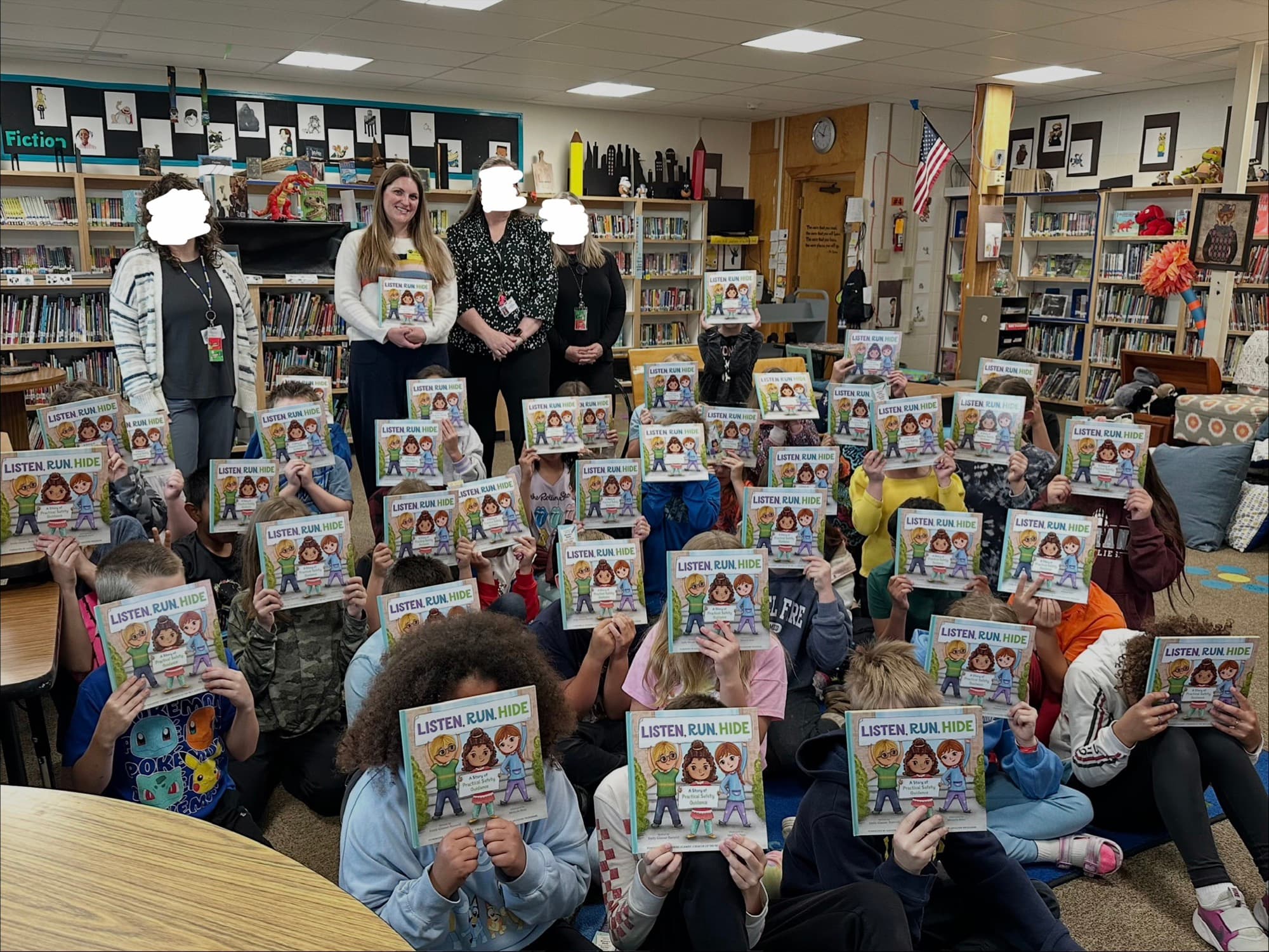 Elementary school students holding up copies of Listen Run Hide during an author visit with Emily Romrell